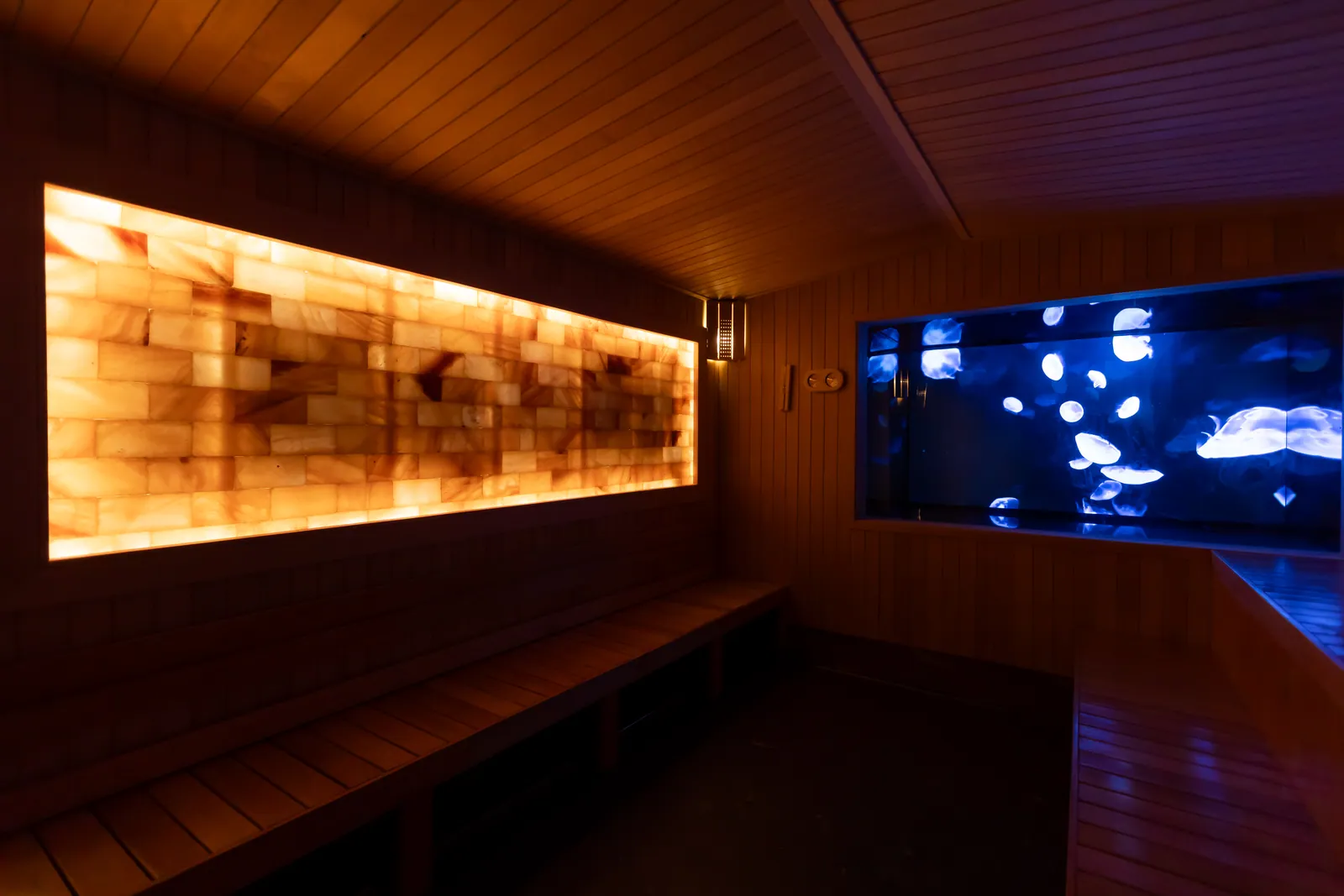 The Immersive Himalayan Salt Sauna at Wellmax gay sauna, Bangkok — a glowing salt brick wall beside a blue digital art panel